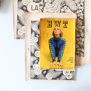 May include: Vintage magazine cover with the letters "BWT" in bold, yellow text. The cover features a woman in a blue sweater with green floral accents. Surrounding the cover are pages with black and white floral and fern patterns.