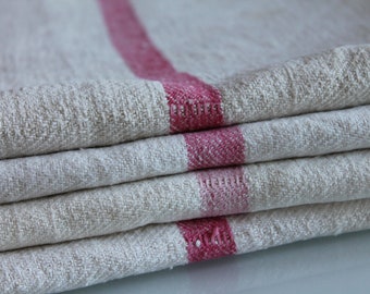May include: Stack of four linen tea towels with a red stripe down the center. The towels are folded and the red stripe is visible on each fold.