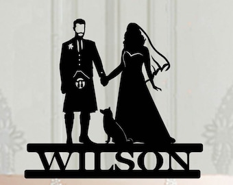 Peut inclure: Topper de gâteau en silhouette noire d'une mariée et d'un marié se tenant la main avec un petit chien. Le marié porte un kilt. Le topper porte le mot "WILSON" écrit sous les figurines.