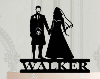 May include: Black silhouette of a bride and groom wedding cake topper with the name "WALKER" on the base.