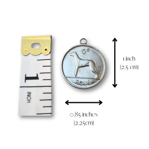 May include: Silver-colored Irish 6d coin pendant with a dog on one side and the word "REUBL" on the other. The coin is 1 inch (2.5 cm) in diameter and 0.85 inches (2.25 cm) wide.