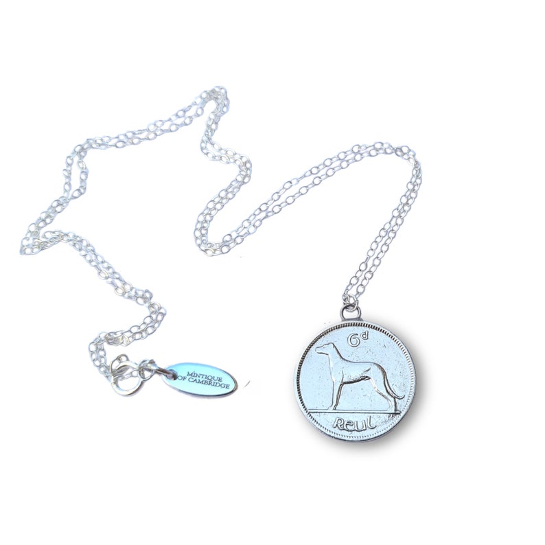 May include: A silver necklace with a silver coin pendant featuring a dog and the text "6d" and "Reul".