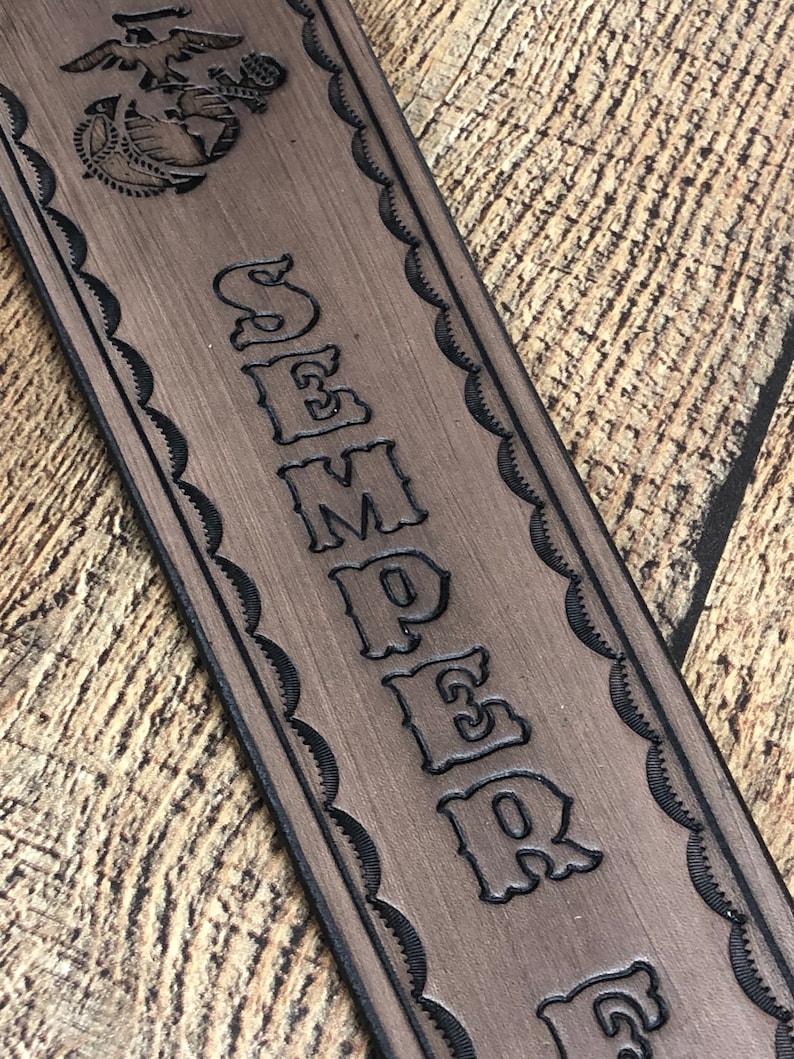 May include: A brown leather guitar strap with a black outline of the Marine Corps emblem and the word "SEMPER FI" in a decorative font.