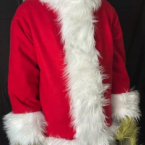 May include: A red costume jacket with white faux fur trim and cuffs. The costume has long sleeves and is worn with a green mask and gloves. The costume is likely for a holiday or character-themed event.