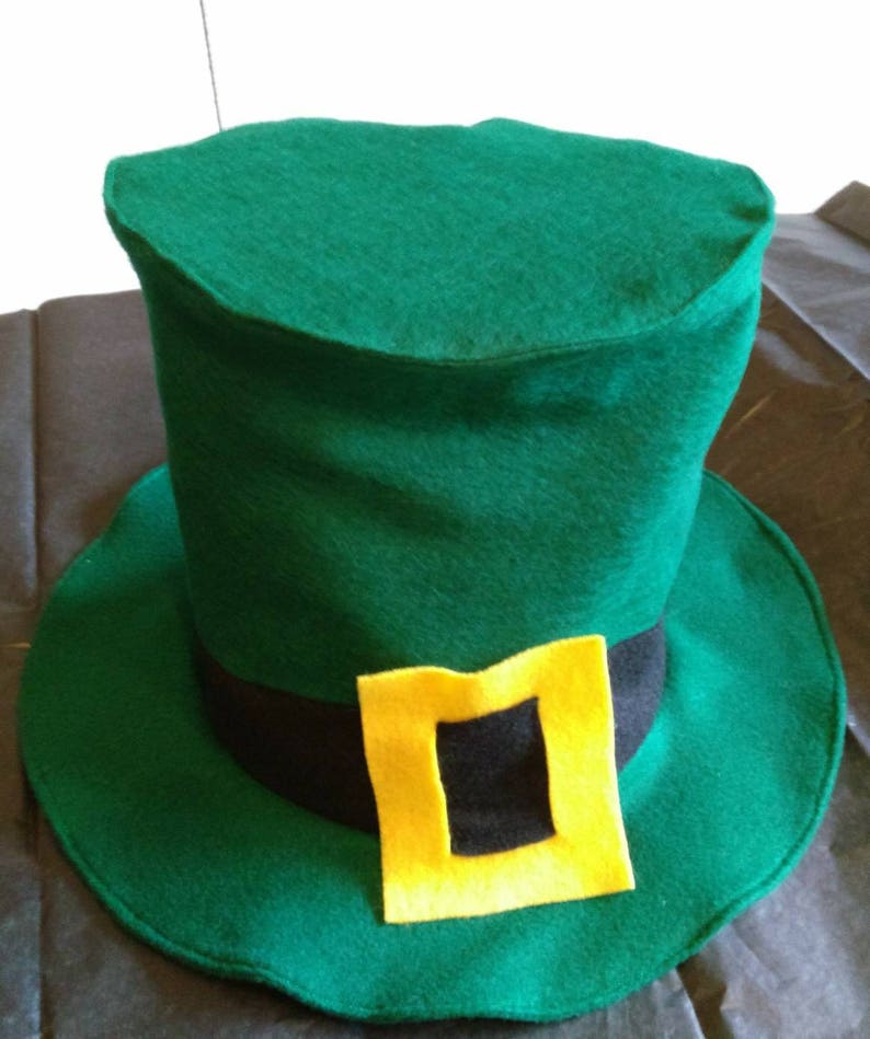 May include: A green felt leprechaun hat with a black band and a yellow buckle. The hat has a tall, cylindrical crown and a wide brim.