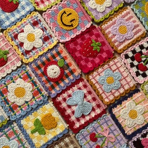 K&ouml;nnte beinhalten: Eine Sammlung farbenfroher, geh&auml;kelter Untersetzer mit verschiedenen Designs. Jeder quadratische Untersetzer zeigt ein anderes Motiv, darunter Blumen, Fr&uuml;chte und ein Smiley. Die Untersetzer haben gewellte Kanten und sind in einem Raster angeordnet.