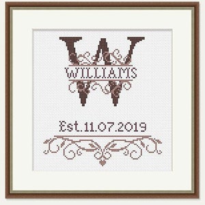 May include: A cross-stitch pattern featuring a monogram with the letter "W" and the name "Williams" below it. The monogram is surrounded by decorative flourishes. The date "Est. 11.07.2019" is below the monogram.