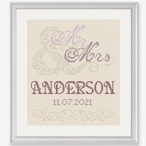 Puede incluir: Un dise&ntilde;o de punto de cruz con las palabras "Mr. & Mrs. Anderson" y la fecha "11.07.2021" en una fuente marr&oacute;n sobre un fondo beige.