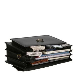 May include: Black leather briefcase, open to reveal contents. The briefcase has a gold-colored clasp and hardware. Inside are books, a wallet, a notepad, and other items. The briefcase is designed with multiple compartments for organization.