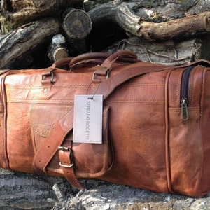 May include: A brown leather duffel bag with a shoulder strap and a zippered pocket. The bag has a label that says "Sergio Rocetti".