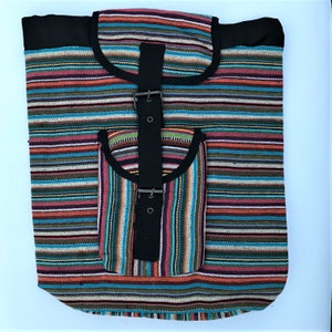 Puede incluir: Una mochila de tela rayada multicolor con una correa de lona negra y una hebilla. La mochila tiene un bolsillo más pequeño en la parte delantera.