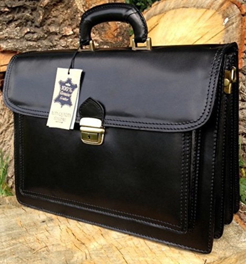 May include: A black leather briefcase with a top handle and a gold-colored clasp. The briefcase has a tag that reads "100% Genuine Leather". The bag is rectangular and has a glossy finish.