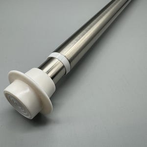 May include: Close-up of a silver tension rod with a white plastic end cap. The end cap has a textured surface and a small hole in the centre.