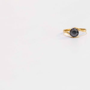 May include: A gold ring with a black gemstone in the center.