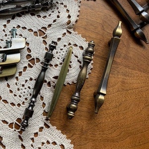 May include: Assortment of cabinet hardware in various styles and finishes.  The hardware includes gold and silver drawer pulls, knobs, and handles.