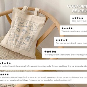 May include: A beige canvas tote bag with a light blue design featuring the text "Steph's Bachelorette Playa del Carmen". The design includes illustrations of a taco, cocktail, palm trees, and beach chair. The bag is hanging on a wooden chair.