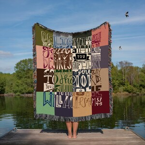 May include: A woven throw blanket with a colourful patchwork design featuring a bible verse: "Delight yourself in the Lord and he will give you the desires of your heart. Commit your way to the Lord, trust in him and he will act." Psalm 37:4-5.