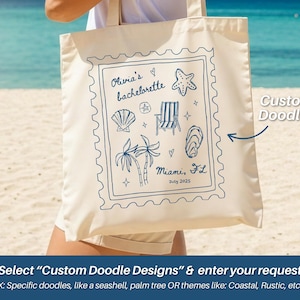 May include: Cream-colored tote bag with a blue doodle design. The design includes a seashell, starfish, beach chair, palm trees, and the text "Olivia's bachelorette" and "Miami, FL July 2025". The bag has a rectangular shape.