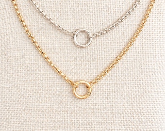 May include: A layered necklace set featuring two separate chains with a rolo link design. The shorter chain is silver-toned with a circular spring ring clasp, while the longer chain is gold-toned and also features a circular spring ring clasp.