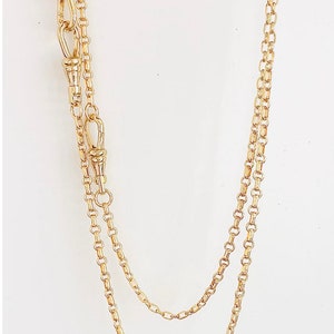 May include: A gold chain necklace with two clasps. The chain is made of small, oval-shaped links.