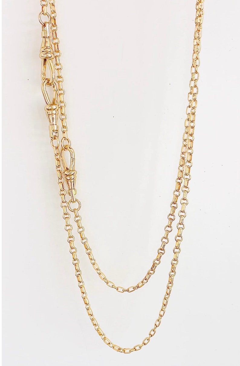 May include: A gold chain necklace with two clasps. The chain is made of small, oval-shaped links.