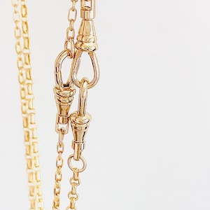 May include: A gold chain necklace with a lobster clasp closure. The chain is made of small, linked circles.