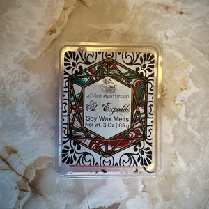 Puede incluir: Un contenedor de plástico transparente con una etiqueta blanca que dice "Le'bleu Apothecary St. Expedite Soy Wax Melts Net wt. 3 Oz | 85 g". La etiqueta tiene un diseño geométrico con acentos rojos, verdes y negros.