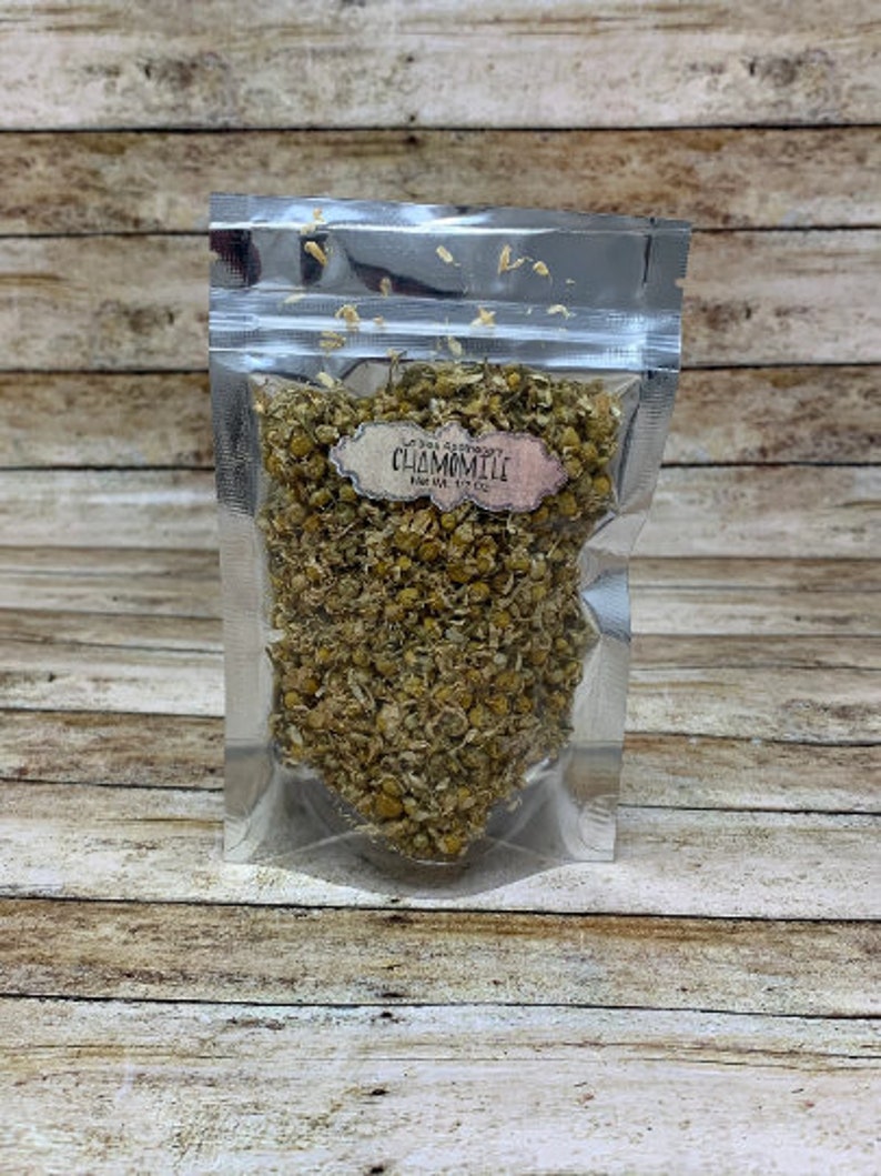 May include: A silver resealable pouch filled with dried chamomile flowers. The pouch has a label that reads "The Herb Sanctuary Chamomile 1 oz (28 g)"