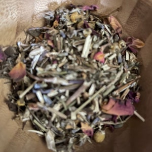 May include: A wooden bowl filled with a blend of dried herbs and flowers, including lavender, chamomile, and rose petals.