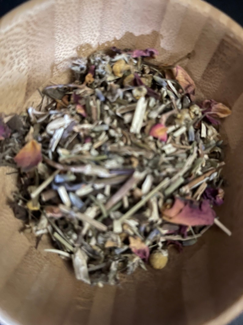 May include: A wooden bowl filled with a blend of dried herbs and flowers, including lavender, chamomile, and rose petals.