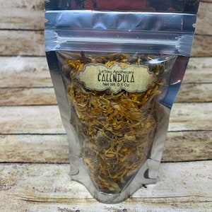 May include: A silver resealable pouch filled with dried calendula petals. The pouch has a label that reads "Le'bleu Apothecary Calendula Net Wt. 0.5 Oz."