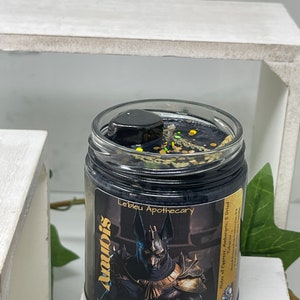 May include: Black candle jar with a gold label that reads "Anubis Mediumship Protection God Of The Dead Le'bleu Apothecary Notes of Cupress, Ambergris, & Dried Tobacco".