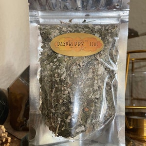 May include: A silver resealable pouch containing dried raspberry leaves. The pouch has a label that reads "Leila's Apothecary Raspberry Leaf Net Wt 0.5 oz."