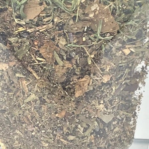 May include: A close-up of a bag filled with dried herbs and leaves. The herbs are a mix of green, brown, and beige.