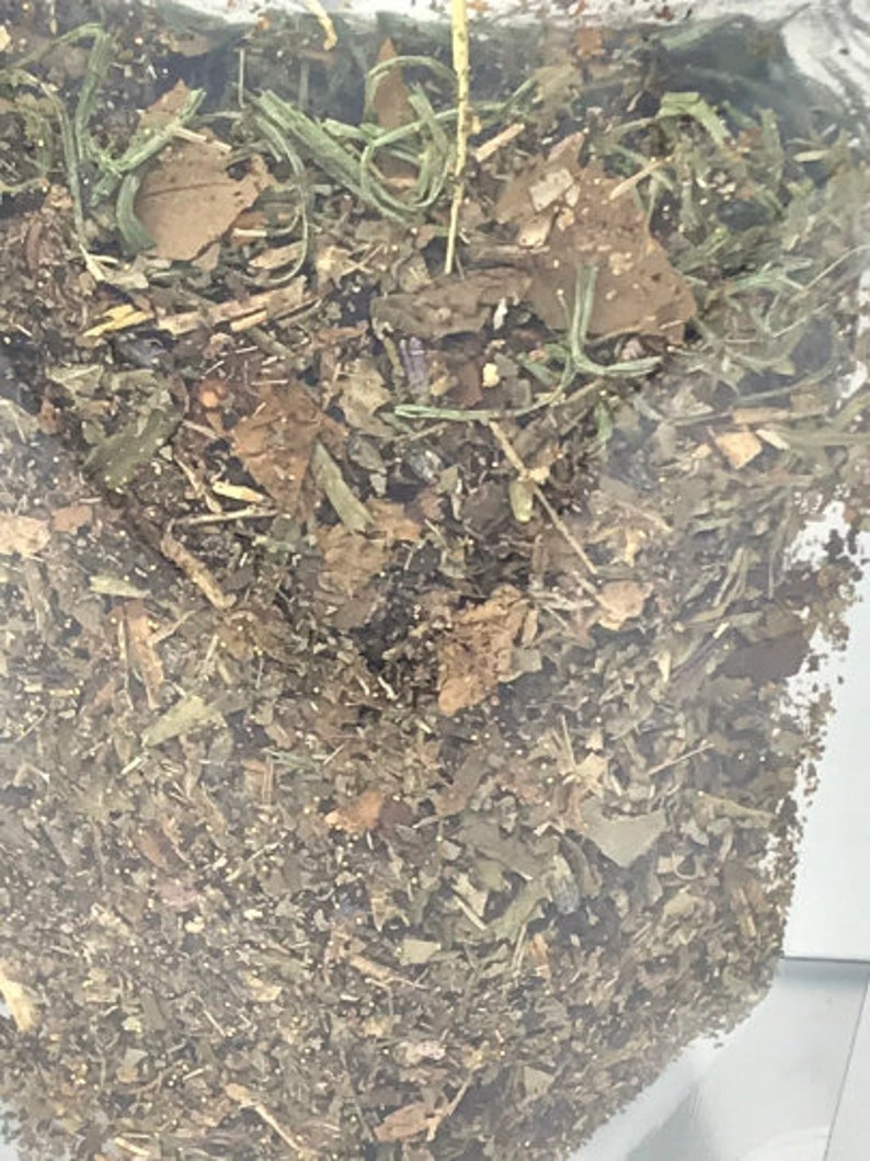 May include: A close-up of a bag filled with dried herbs and leaves. The herbs are a mix of green, brown, and beige.