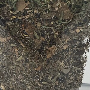 May include: A close-up of a bag filled with dried herbs and leaves. The herbs are a mix of brown, green, and yellow.