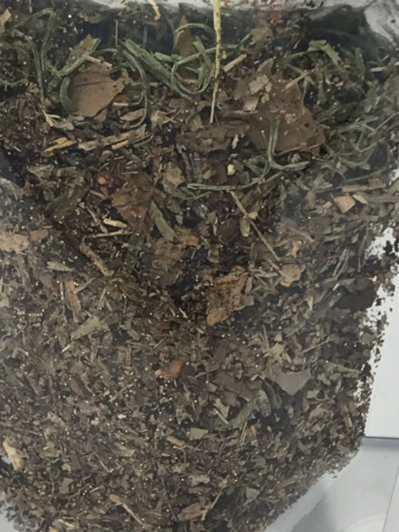 May include: A close-up of a bag filled with dried herbs and leaves. The herbs are a mix of brown, green, and yellow.