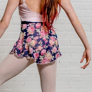 Op de afbeelding: Een roze en witte maillot met een navy blauwe rok met bloemenprint. De rok heeft een gerimpelde zoom en is gemaakt van een transparante stof.