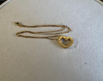 May include: A gold necklace with a heart-shaped pendant. The pendant is open and has small diamonds around the edge.