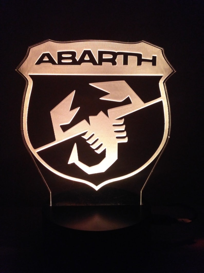 May include: A black and white illuminated sign with the word "ABARTH" and a scorpion logo.