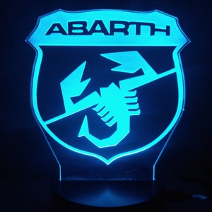 May include: A blue illuminated sign with the word "ABARTH" and a scorpion logo.