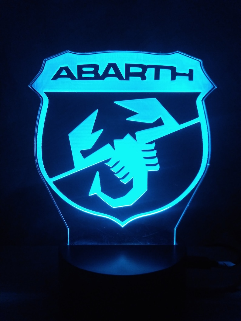 May include: A blue illuminated sign with the word "ABARTH" and a scorpion logo.