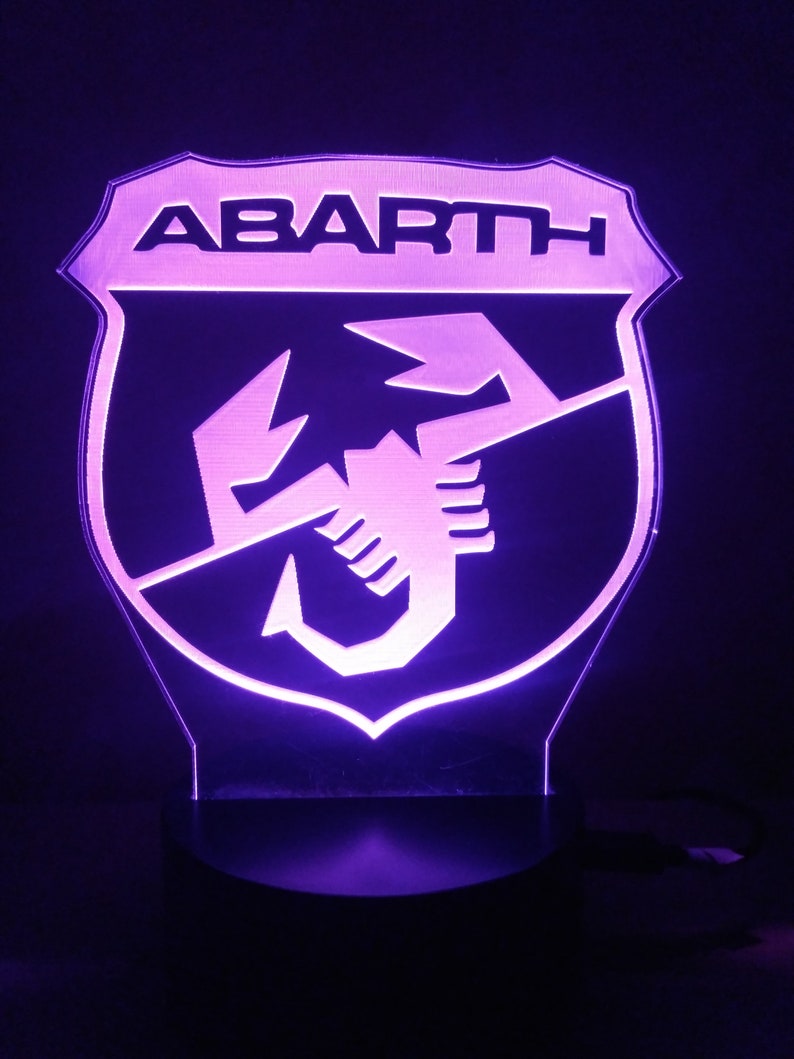 May include: A purple illuminated sign with the word "ABARTH" and a scorpion logo.
