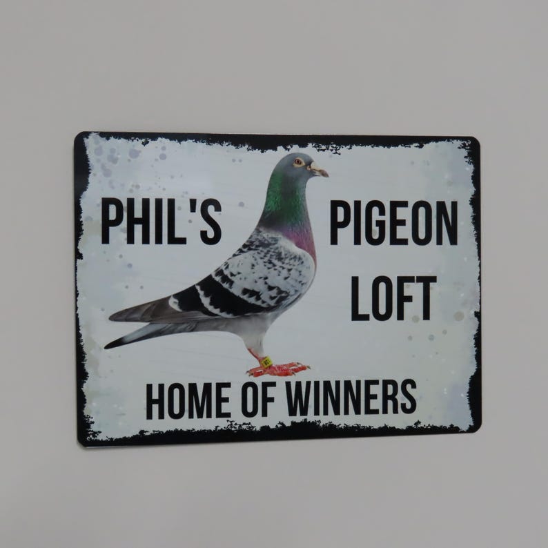 May include: A black and white sign with the text "Phil's Pigeon Loft Home of Winners" and a picture of a pigeon.