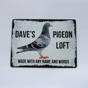 May include: A white metal sign with black text and a picture of a pigeon. The sign says "Dave's Pigeon Loft" and "Made with any name and words".