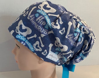 May include: Blue scrub hat with a white bone pattern and the text "Ortho Surgery is Hip & Humerus".