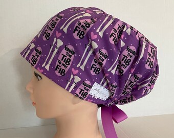 May include: Purple surgical scrub hat with a white bone pattern and the text "You're the Tib to my Fib" repeated throughout. The hat has a purple ribbon tie.