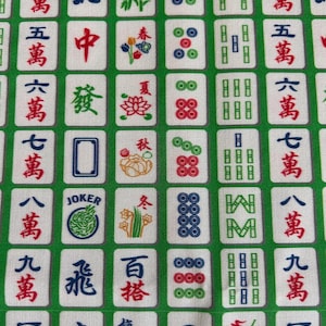 Pode incluir: Uma imagem de perto de um tecido verde e branco com um padr&atilde;o repetido de pe&ccedil;as de Mahjong. As pe&ccedil;as exibem caracteres chineses, n&uacute;meros e s&iacute;mbolos em vermelho, azul e verde. O tecido tem um design semelhante a uma grade.