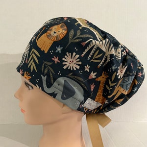May include: A dark blue scrub hat with a colorful print of animals and flowers. The animals include a lion, zebra, elephant, and giraffe. The hat has a brown tie.