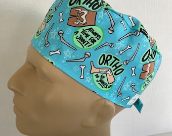 May include: A light blue surgical scrub hat with a pattern of bones, stars, and the text "ORTHO", "ALWAYS TIME FOR A JOINT!" and "WE DO JOINTS!"
